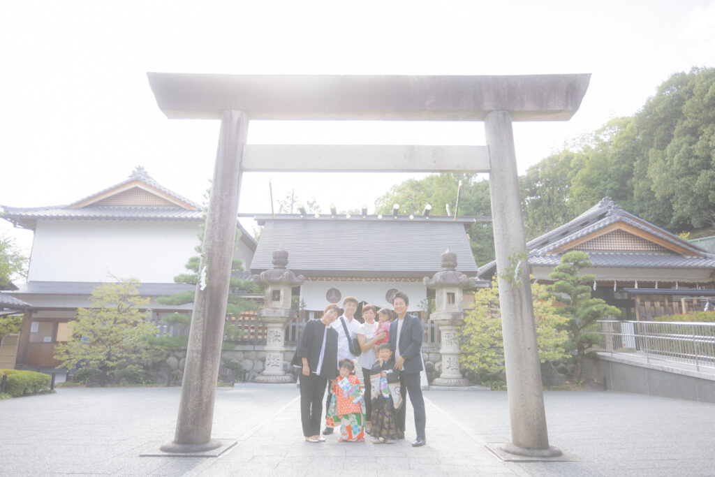 塩竈神社の本殿前の大きな鳥居をバックにした七五三の家族写真